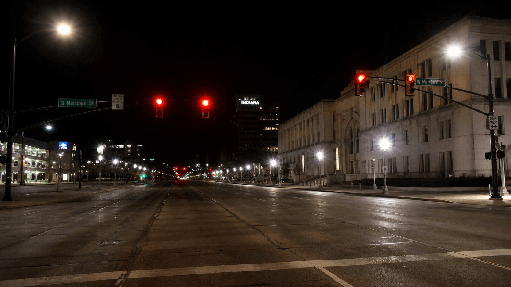Traffic signal glowing red at a wide Indianapolis intersection at night, the type of signalized crossing where a fatal red-light crash occurred on the city's north side