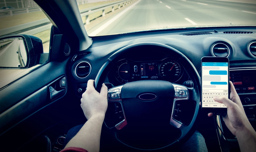 A person driving on a highway texts while driving.