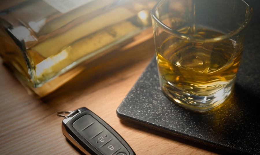 A glass of liquor sits on a table next to a car key.