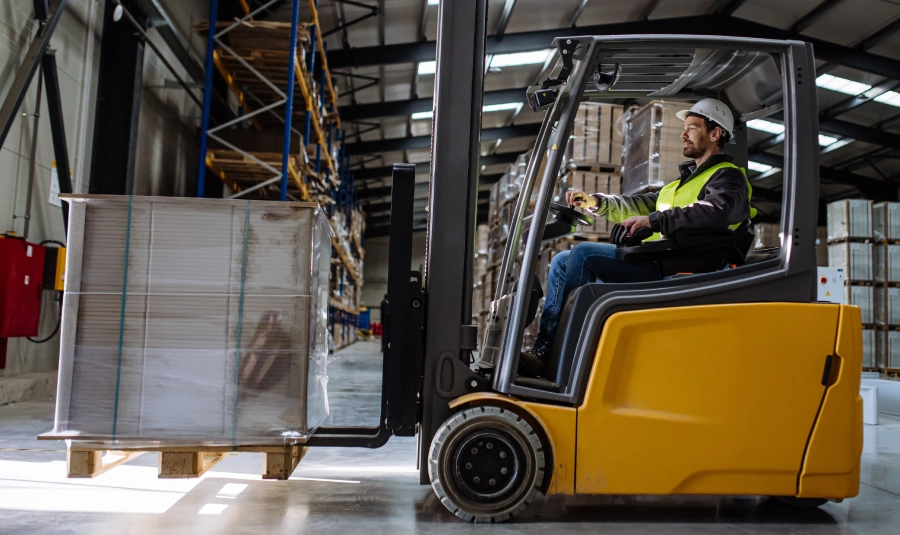 A man operates a forklist in a warehouse.