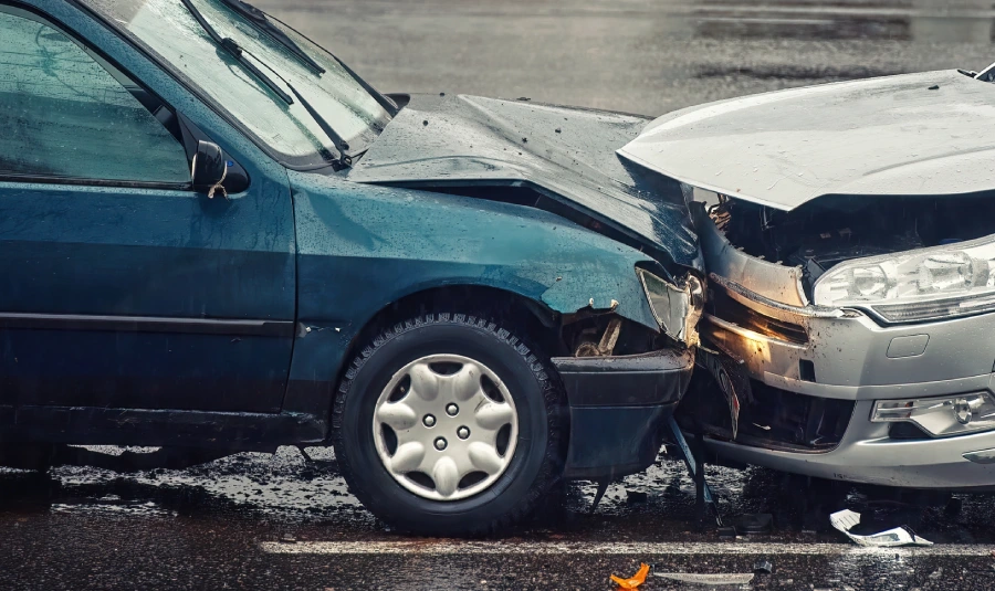 Two cars sit in the road damaged after a head-on collision.