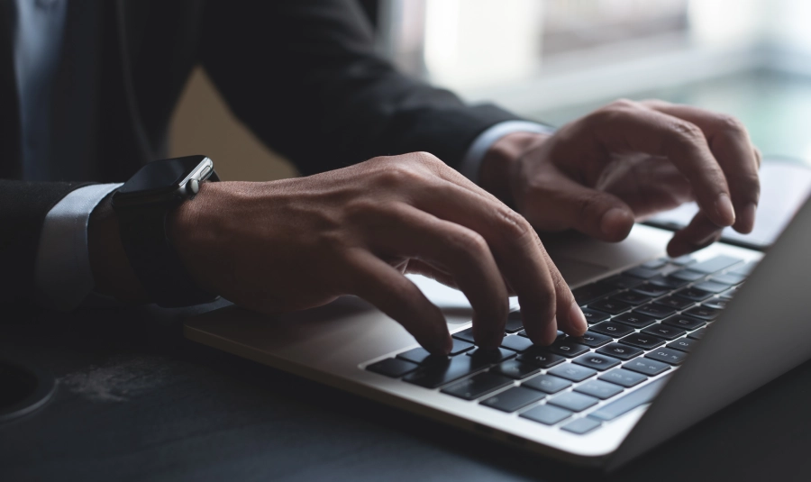 A man in a suit types on his laptop.