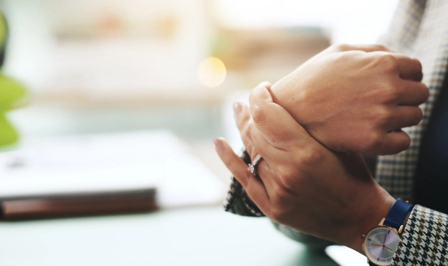 A woman holds her wrist as if in pain.