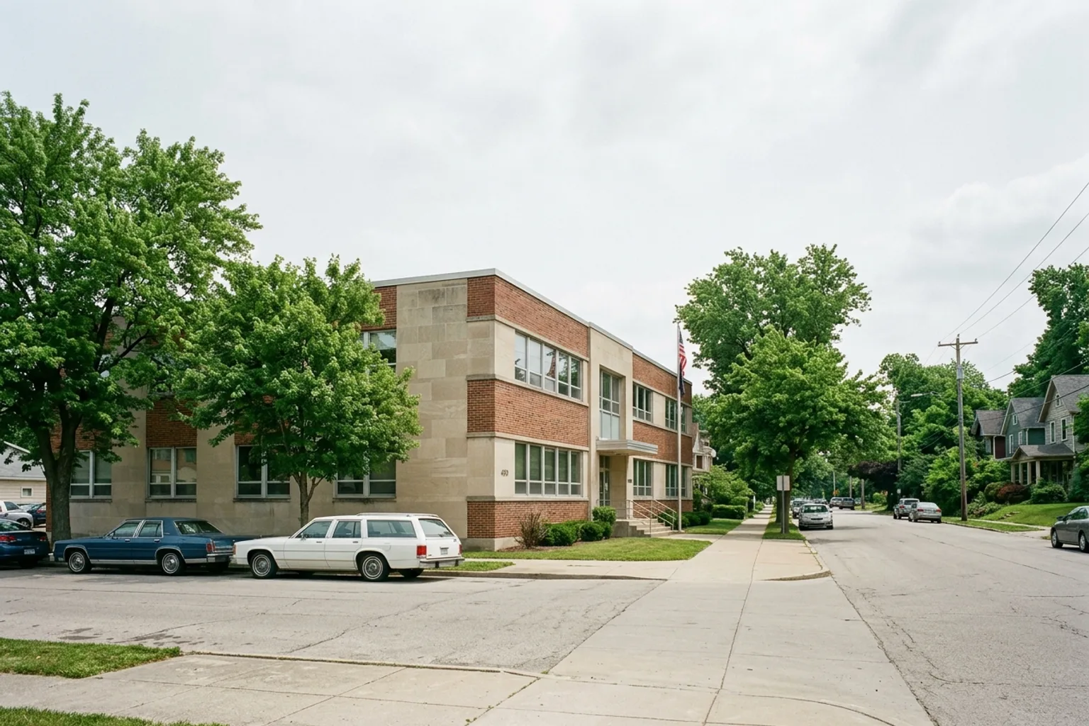 Exterior of a modest brick office building beside a sidewalk and parking area