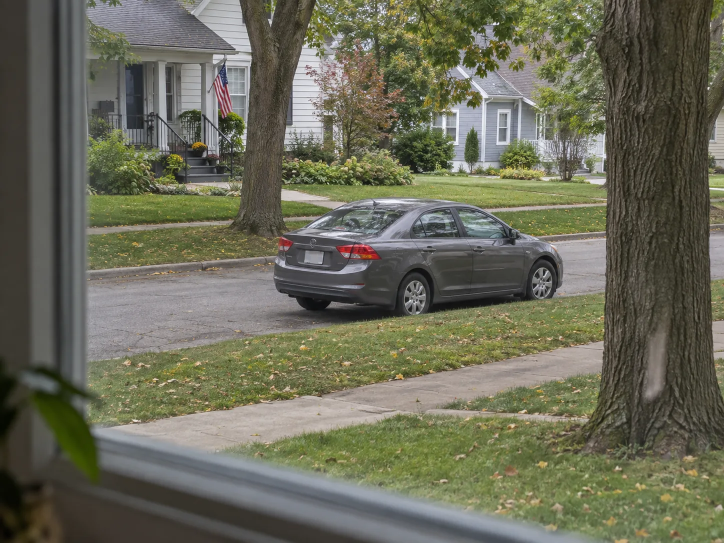 Unfamiliar vehicle parked on a residential street as seen safely from inside a home