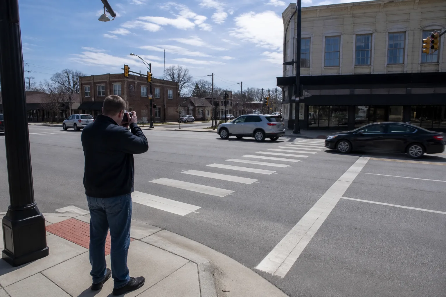 Pedestrian documenting a Fort Wayne crosswalk with a phone