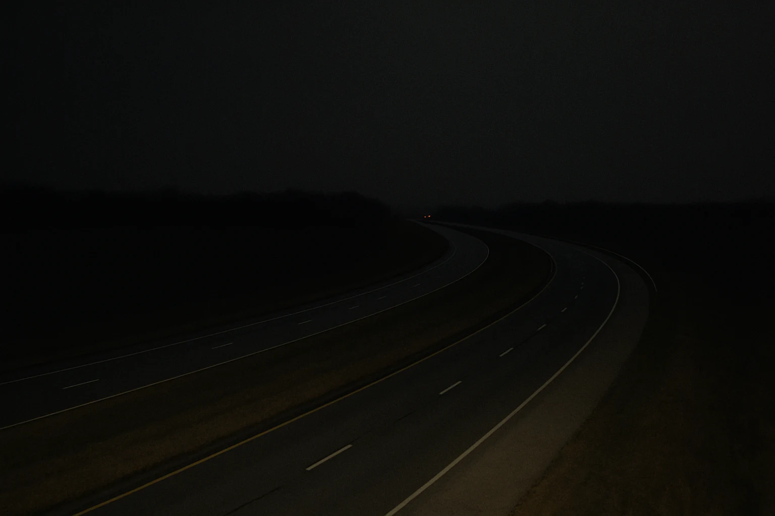 Long stretch of I-69 in northern Indiana at night with the taillights of a single distant vehicle