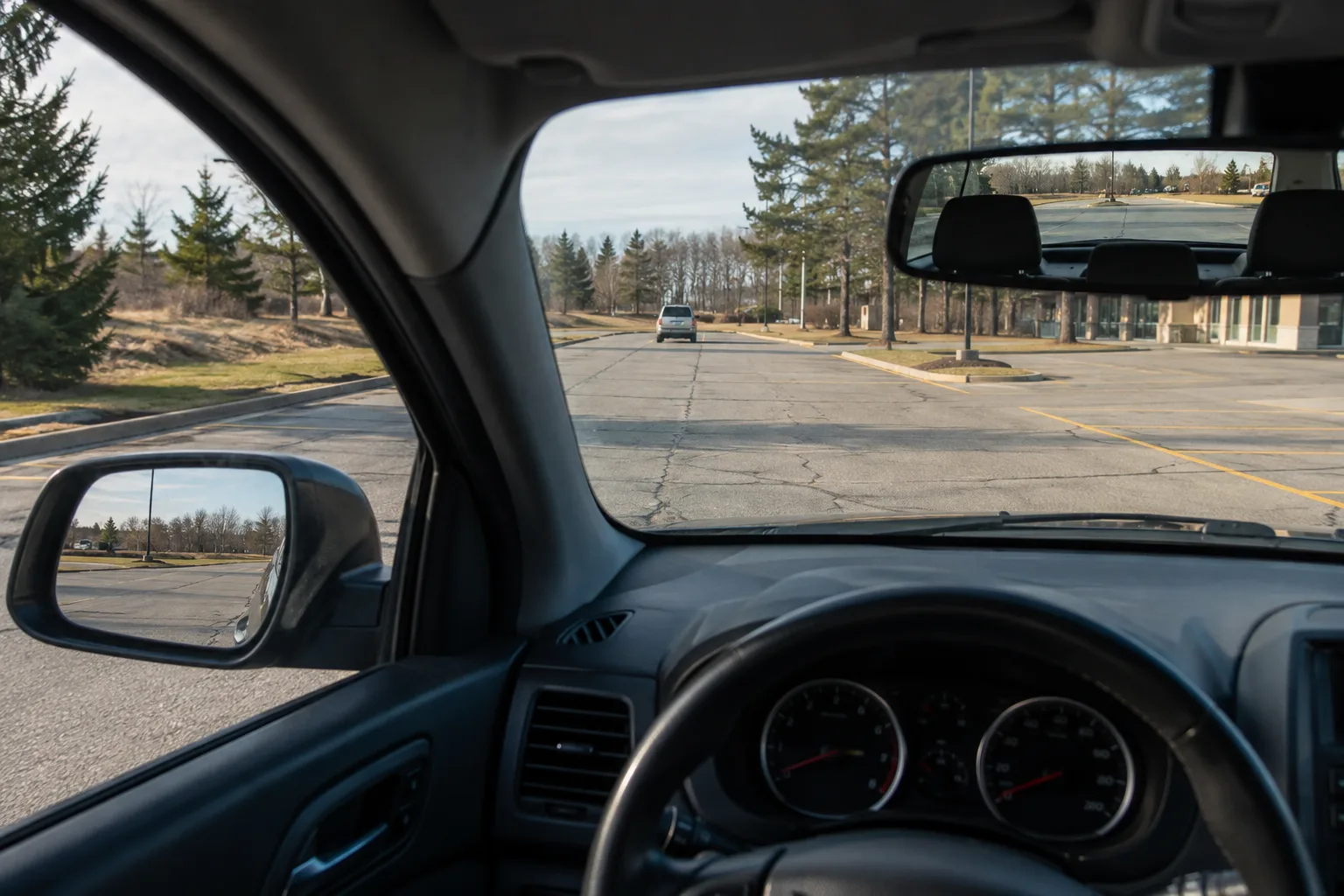 Driver’s view through mirrors toward a parking-lot travel aisle.