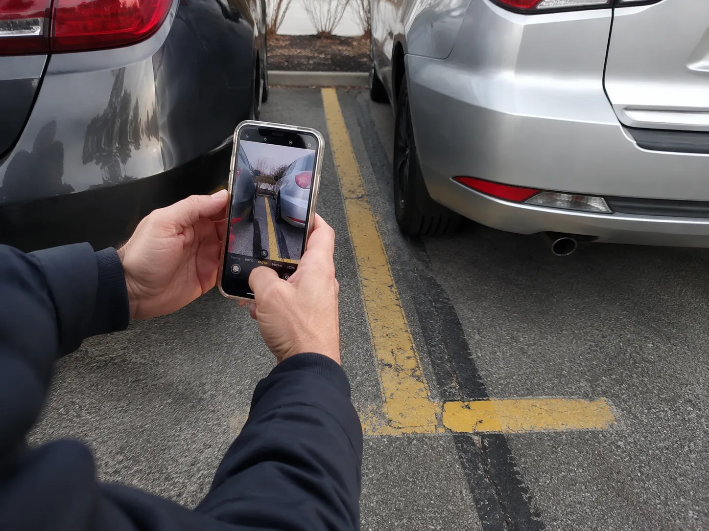 A person photographs vehicle positions and parking-lot markings.