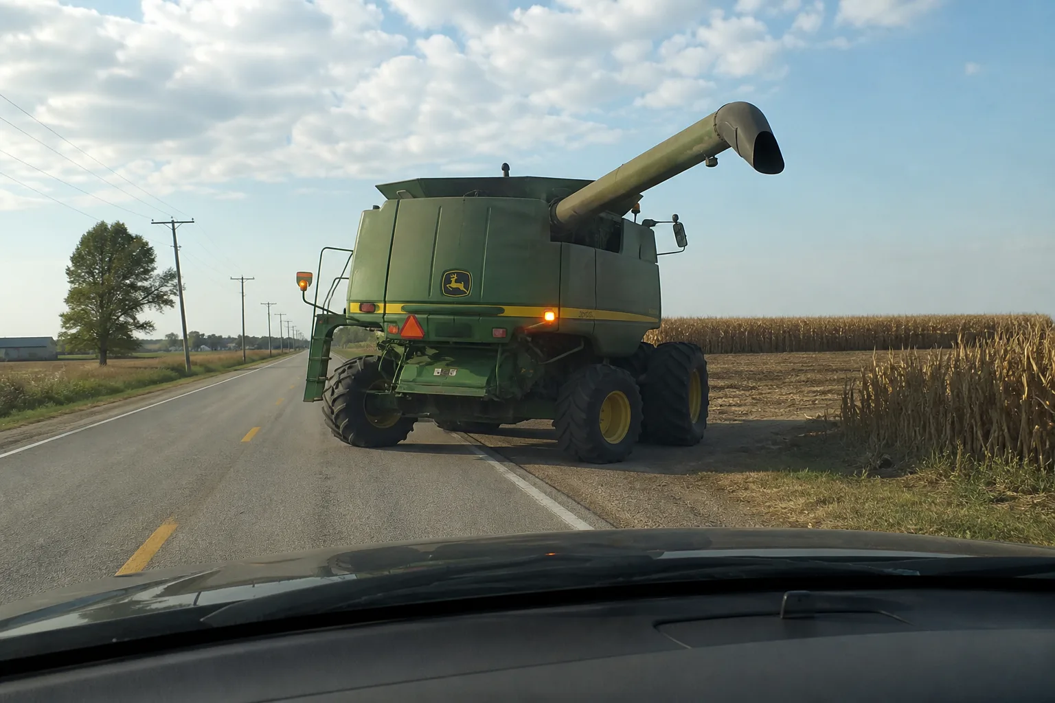 Wide combine preparing to turn from a northeast Indiana road into a field entrance.