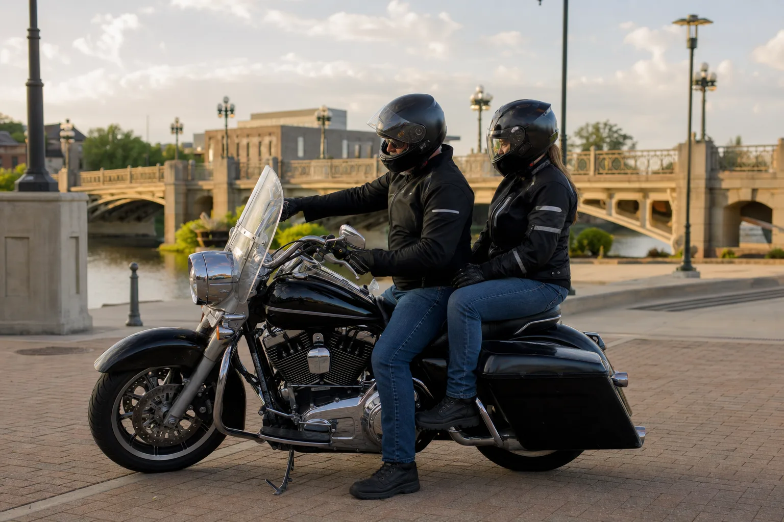 Motorcycle rider and adult passenger using proper seating and protective gear near the Fort Wayne riverfront