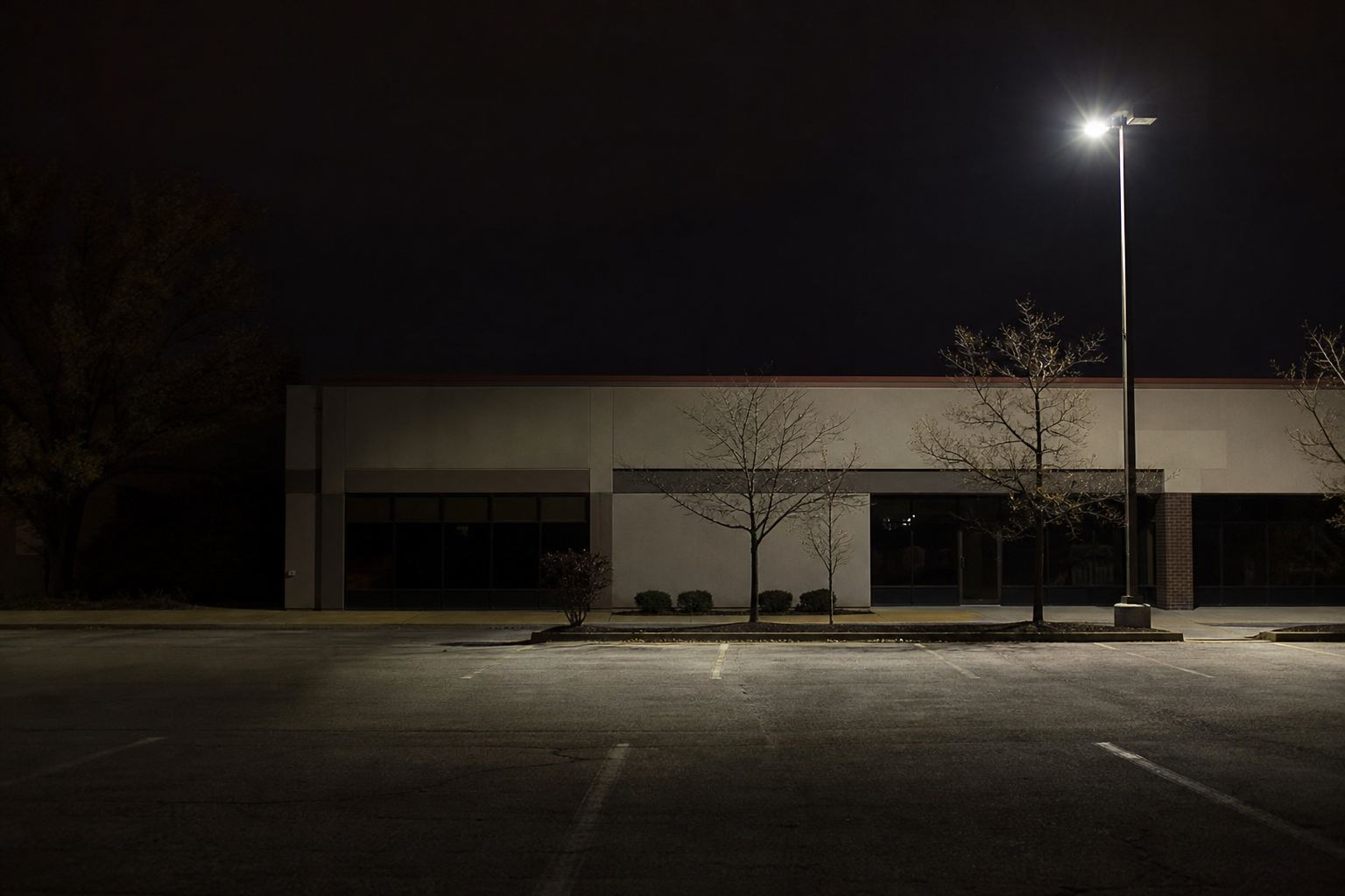 Dimly lit business parking lot at night in Fort Wayne with a single flickering light