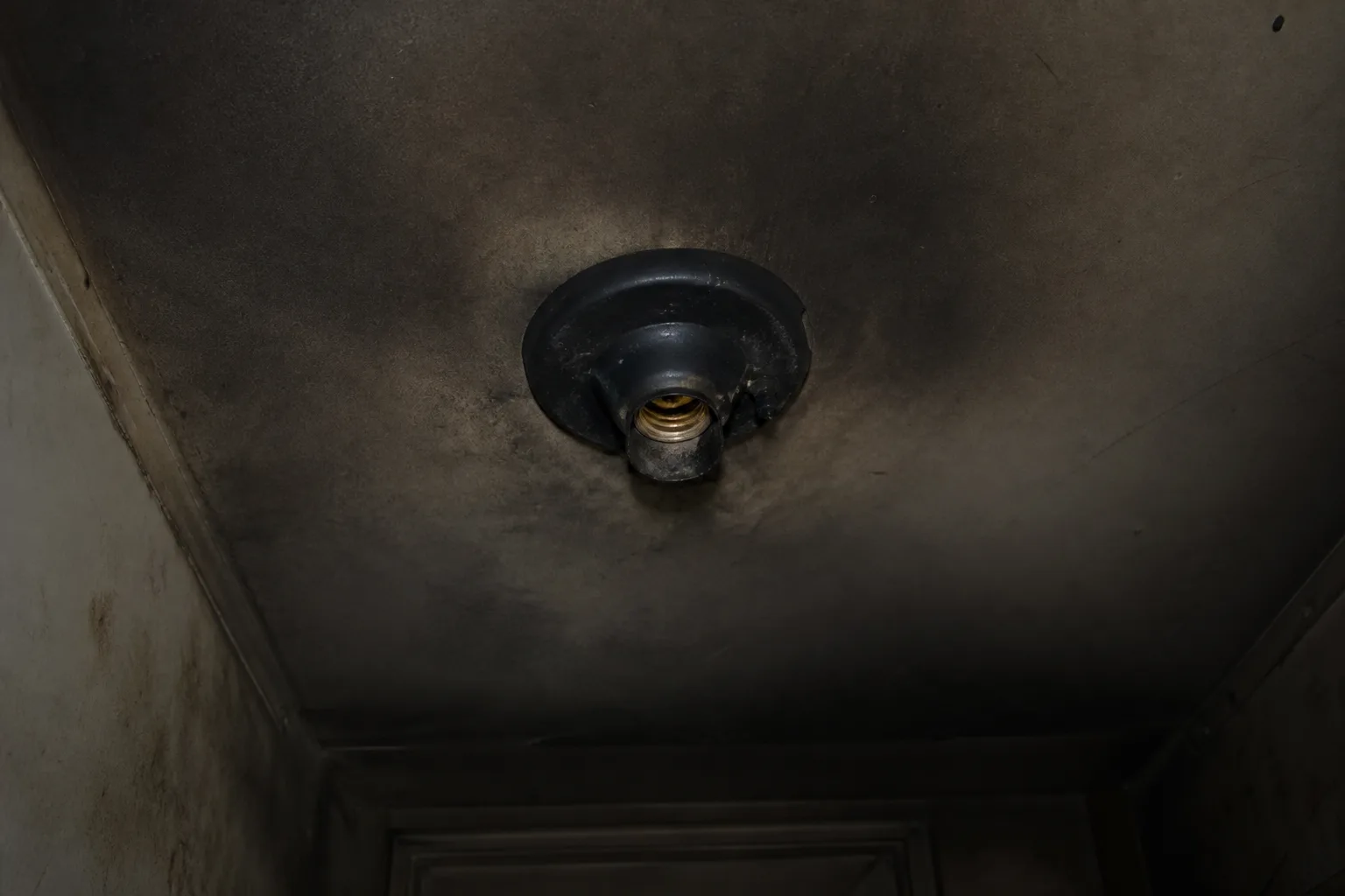 Burned-out overhead light fixture in a dark building hallway