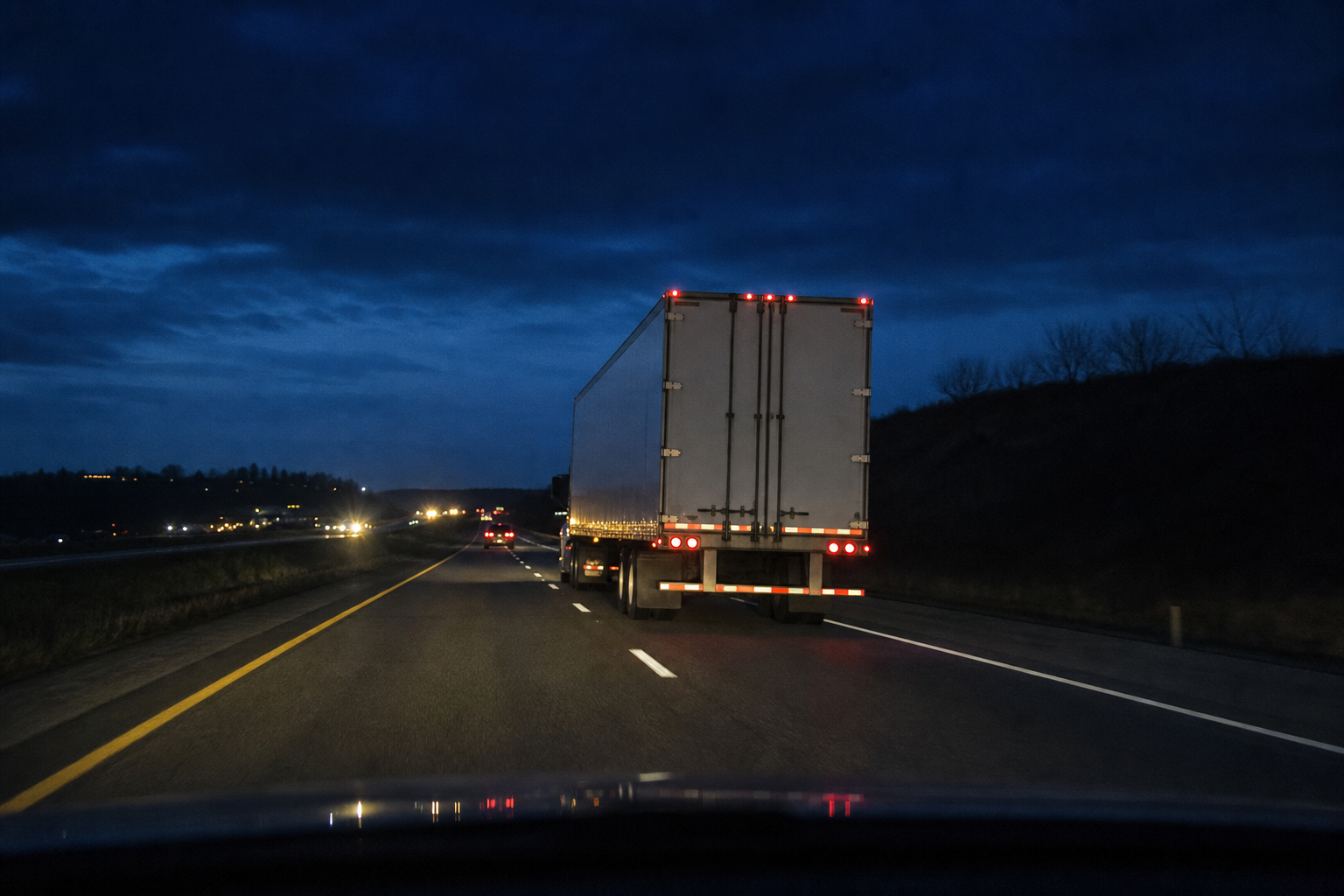 Passenger vehicle keeping distance behind semi truck at dusk on an Indiana highway