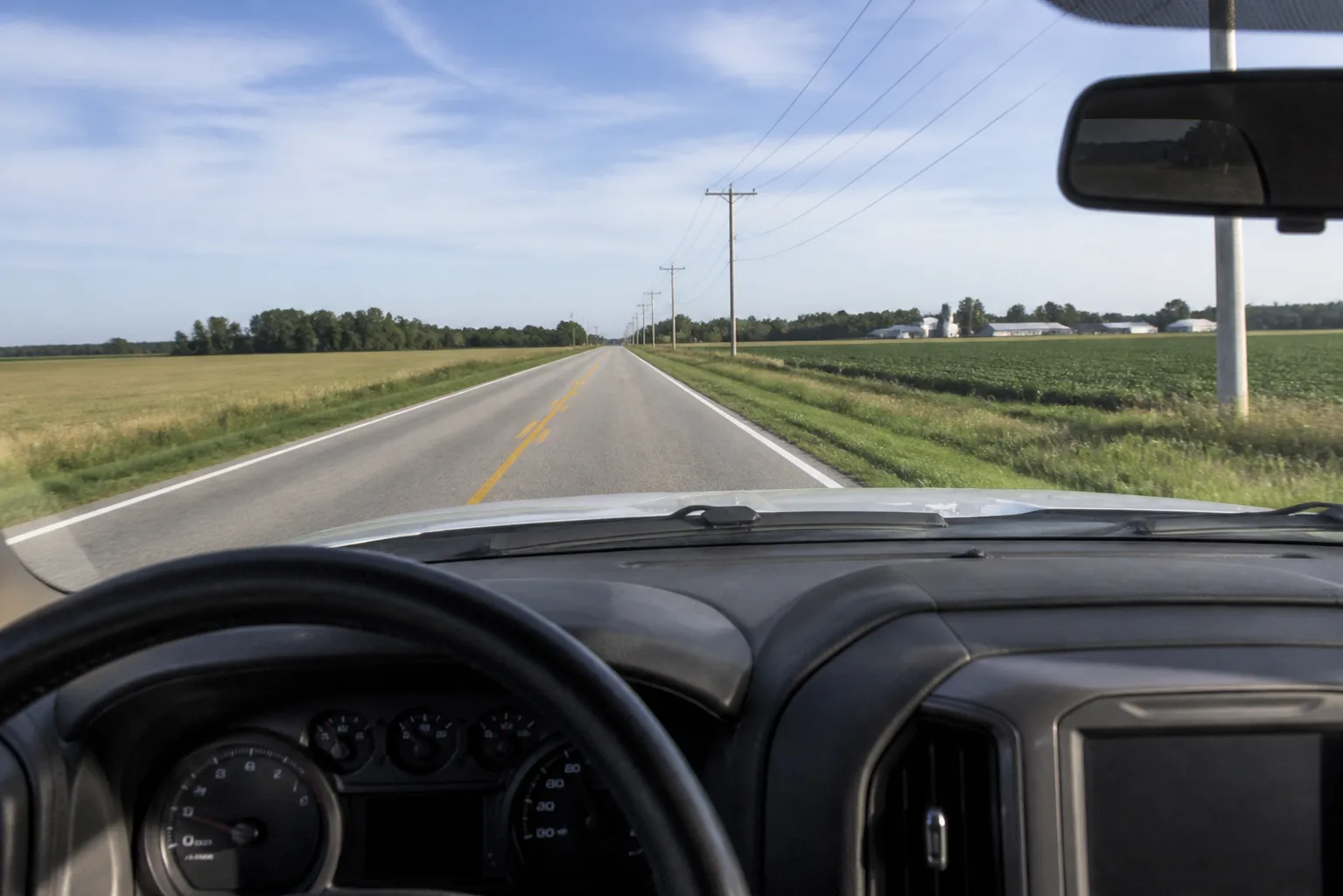 View from inside a work pickup truck driving on a rural northeast Indiana highway during a workday