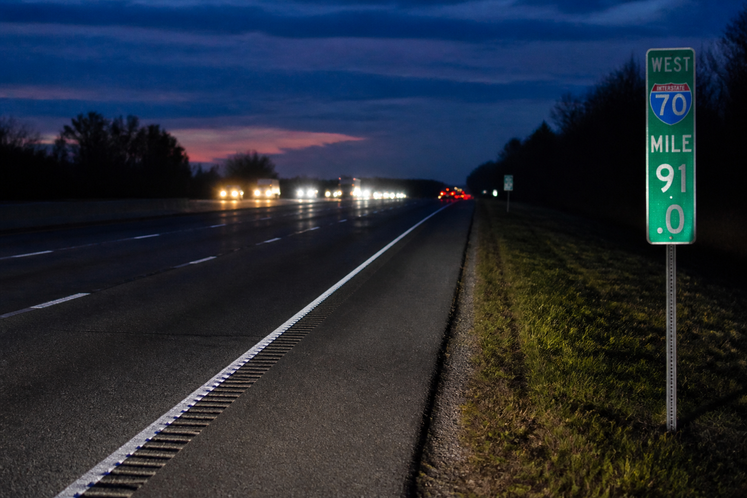 A nighttime interstate shoulder and mile marker illustrating roadside dangers along I-69 near Fishers, Indiana.