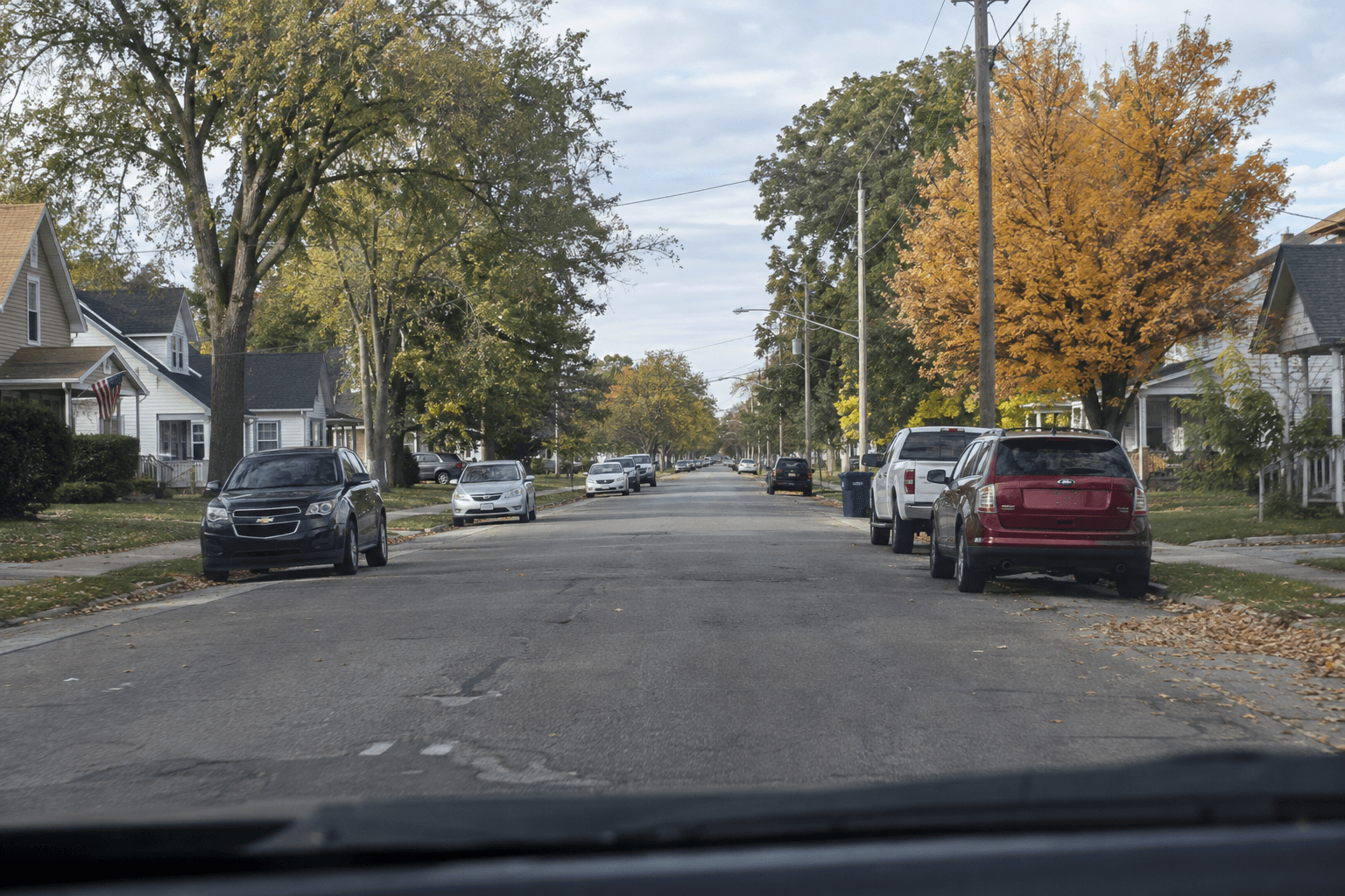 Parked vehicles along a residential Elkhart street illustrate the roadway setting of the W. Franklin Street distraction crash.