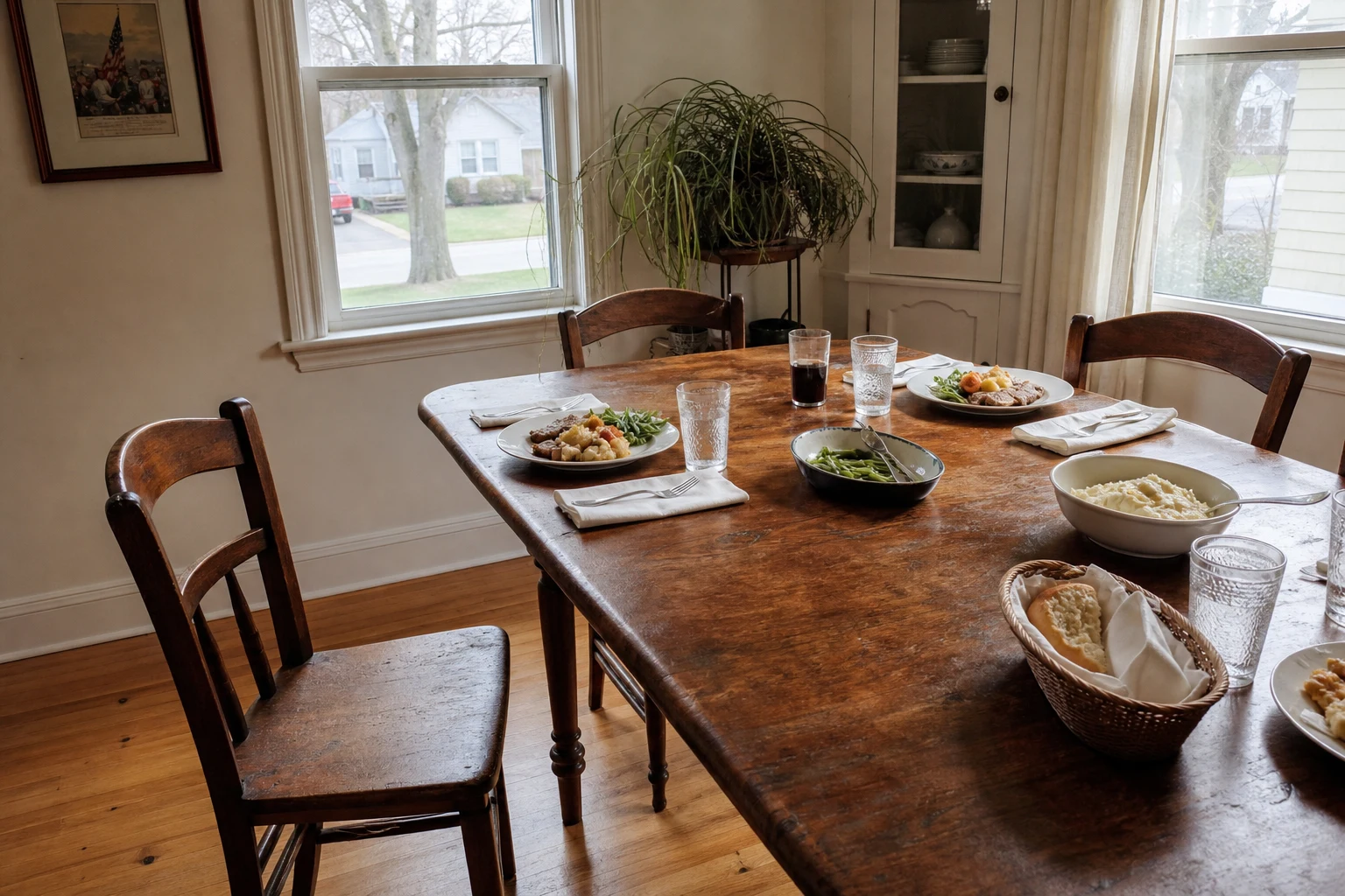 Wooden dining table set for a family meal with one empty chair pulled out and no place setting in front of it — what surviving family members live with in every Fort Wayne wrongful death case