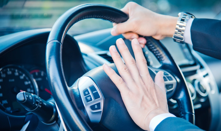 A business man has his hand on his horn while driving.