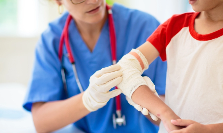 A child's elbow is wrapped as a medical professional attends to it.