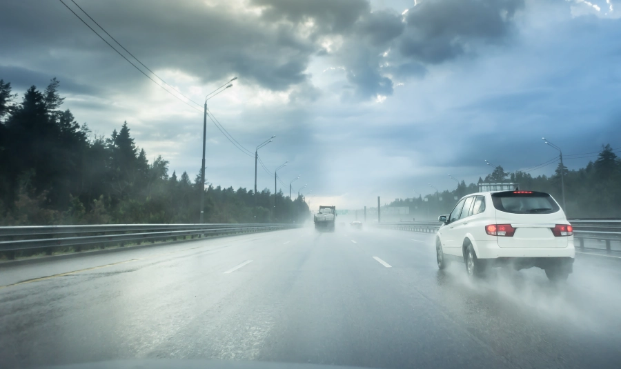 First-person view on driving on a wet highway in light traffic.