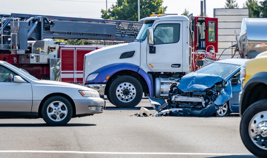 A damaged car sits surrounded by many other vehicles.