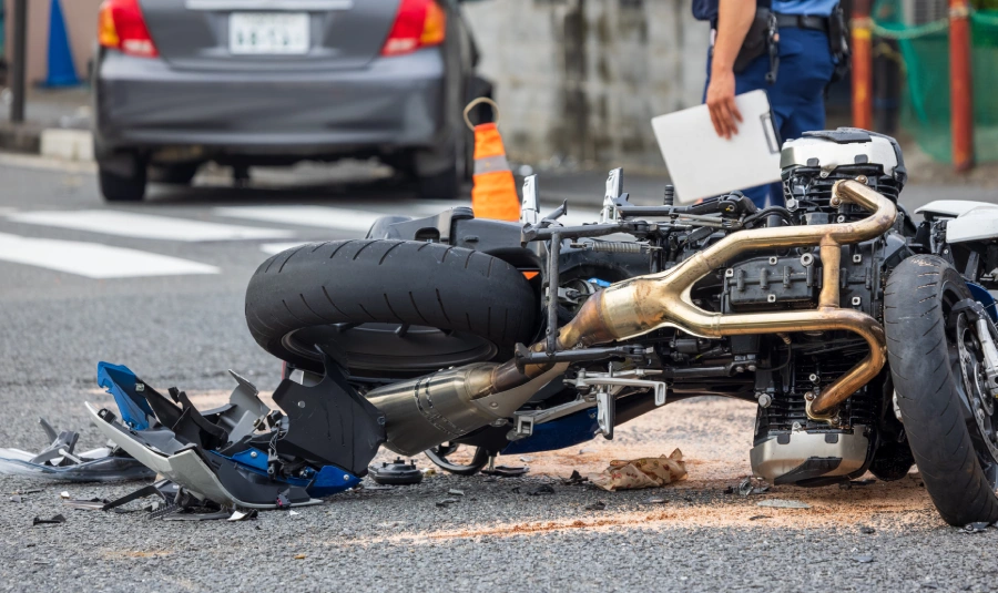 A damaged motorcycle lays on its side in the road.